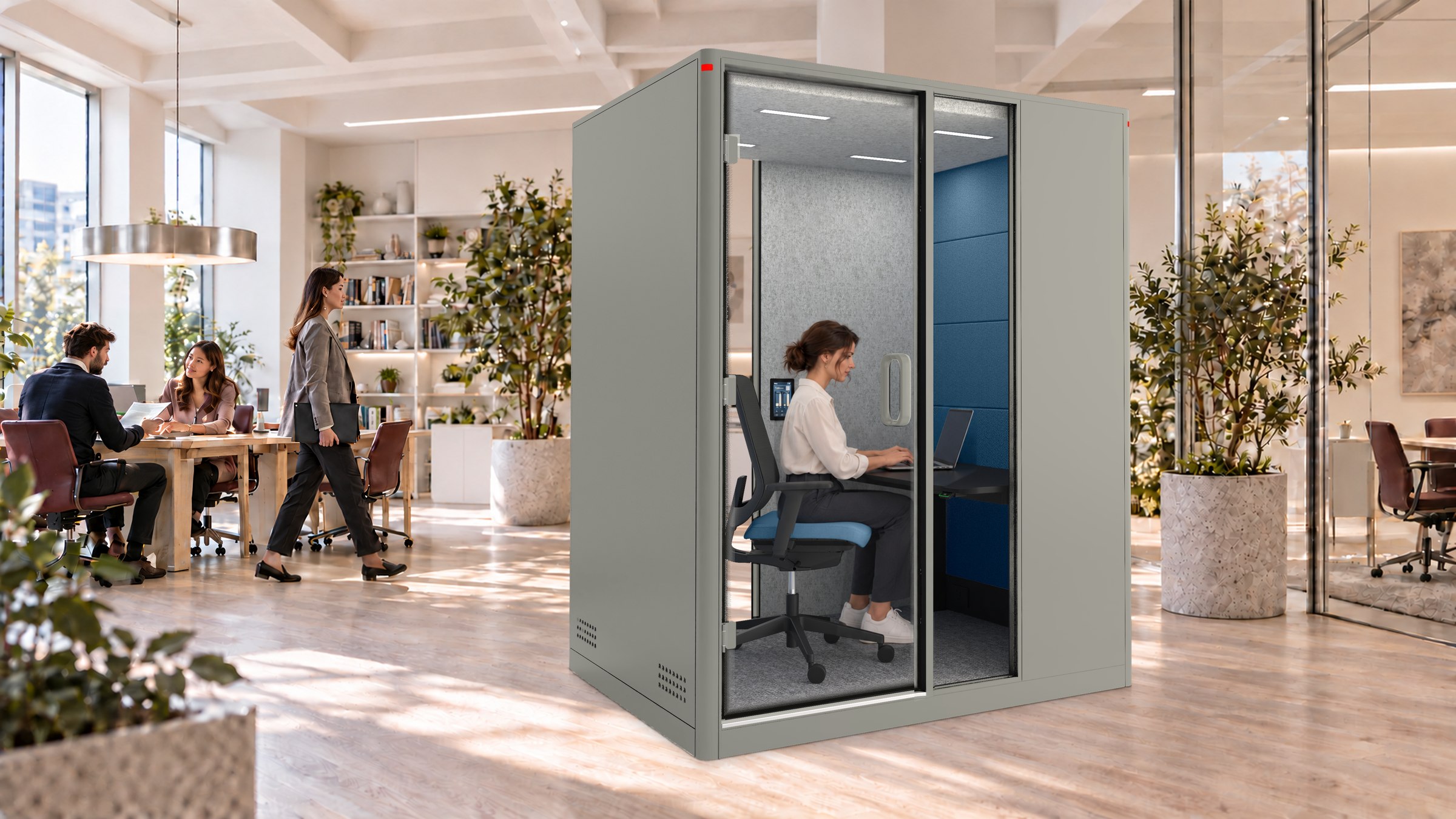 A Calma Focus pod in a bright editorial office, a woman working at the desk inside while colleagues work at the tables behind