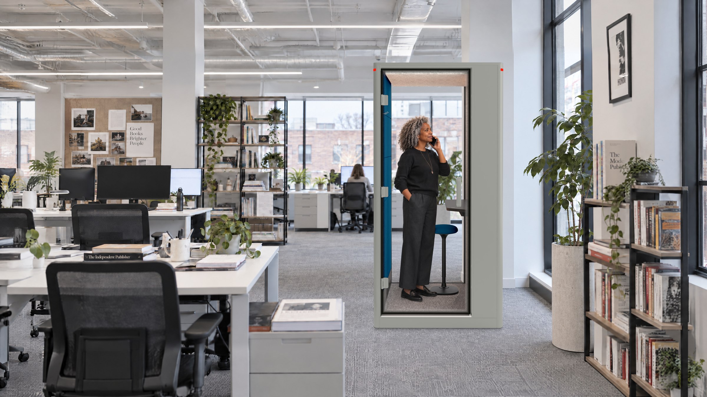 A Calma Small pod in a publishing house, a woman on a call inside while editors work at the desks around it