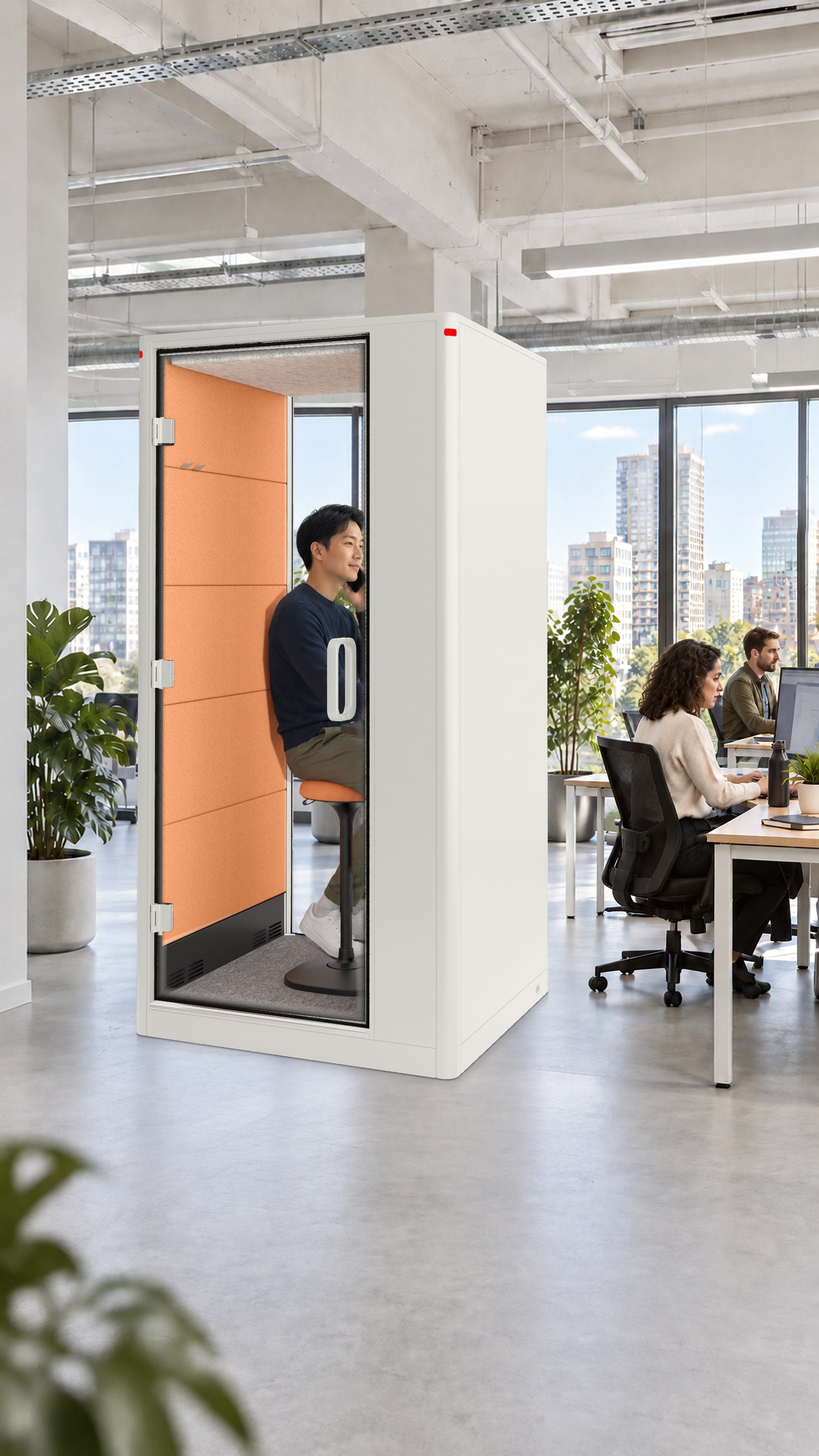 A Calma Small pod in a start-up office, a man on a call inside, colleagues at the desks behind