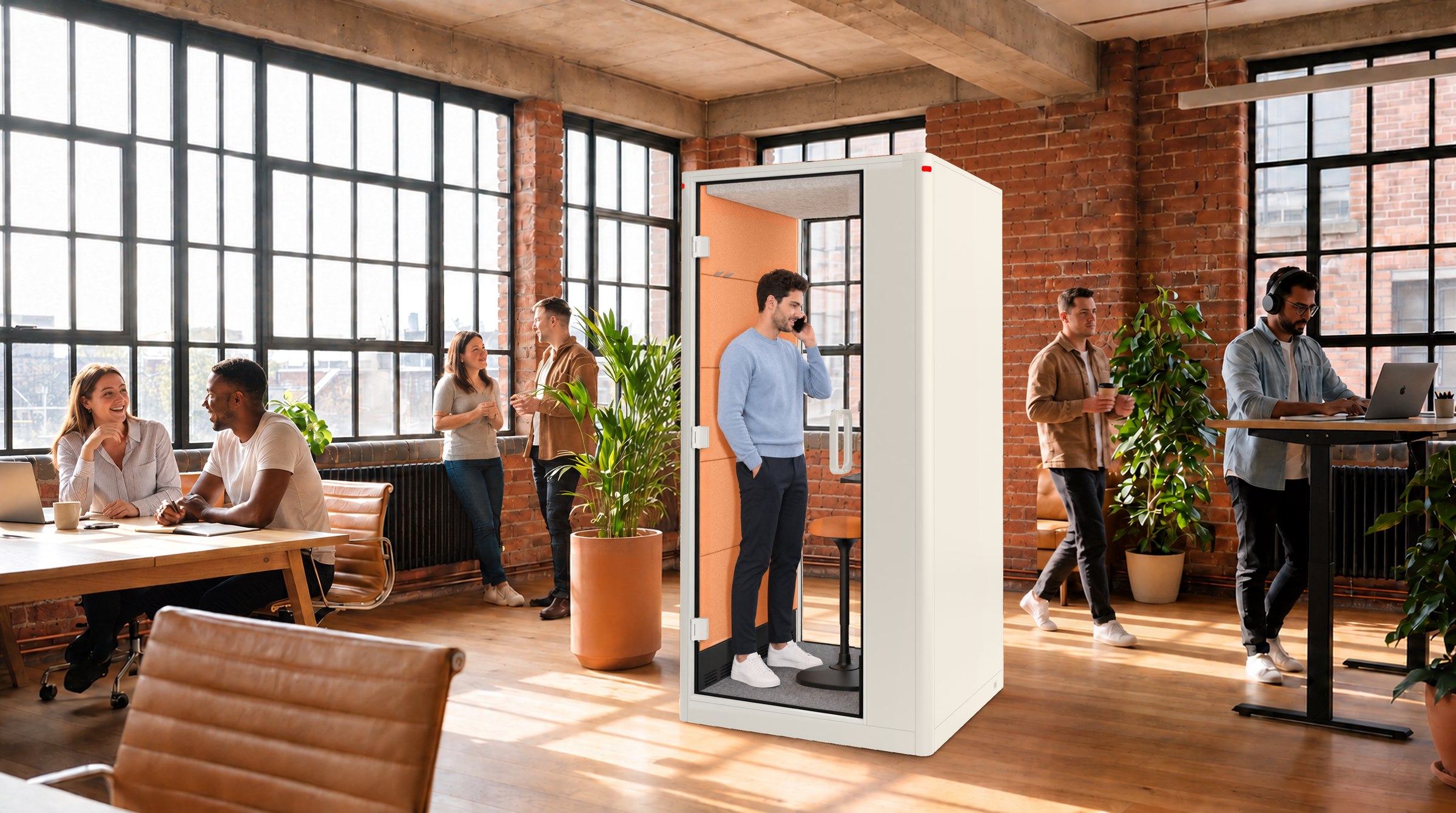 A Calma Small pod in use in a bright loft office, a man on a call inside